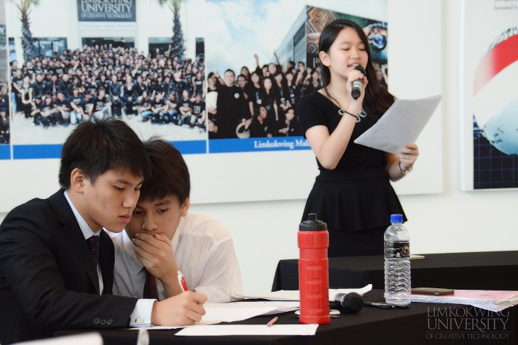 Opening Opposition's Eliza Chow take the stage, while Opening Government's Kenneth Foo and Ng Yong Sheng deliberate their next argument