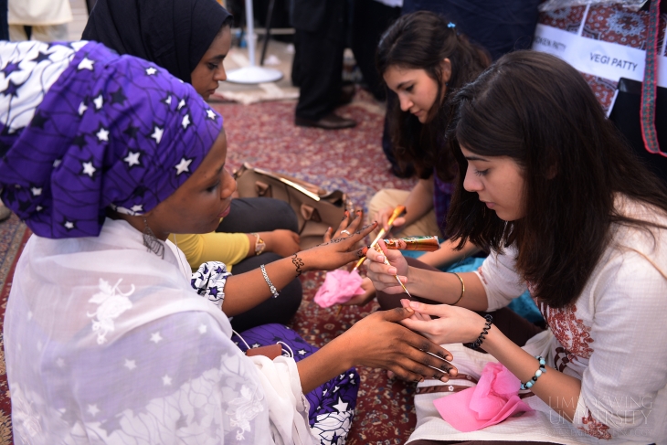 Students trying henna hand art at the Pakistan booth